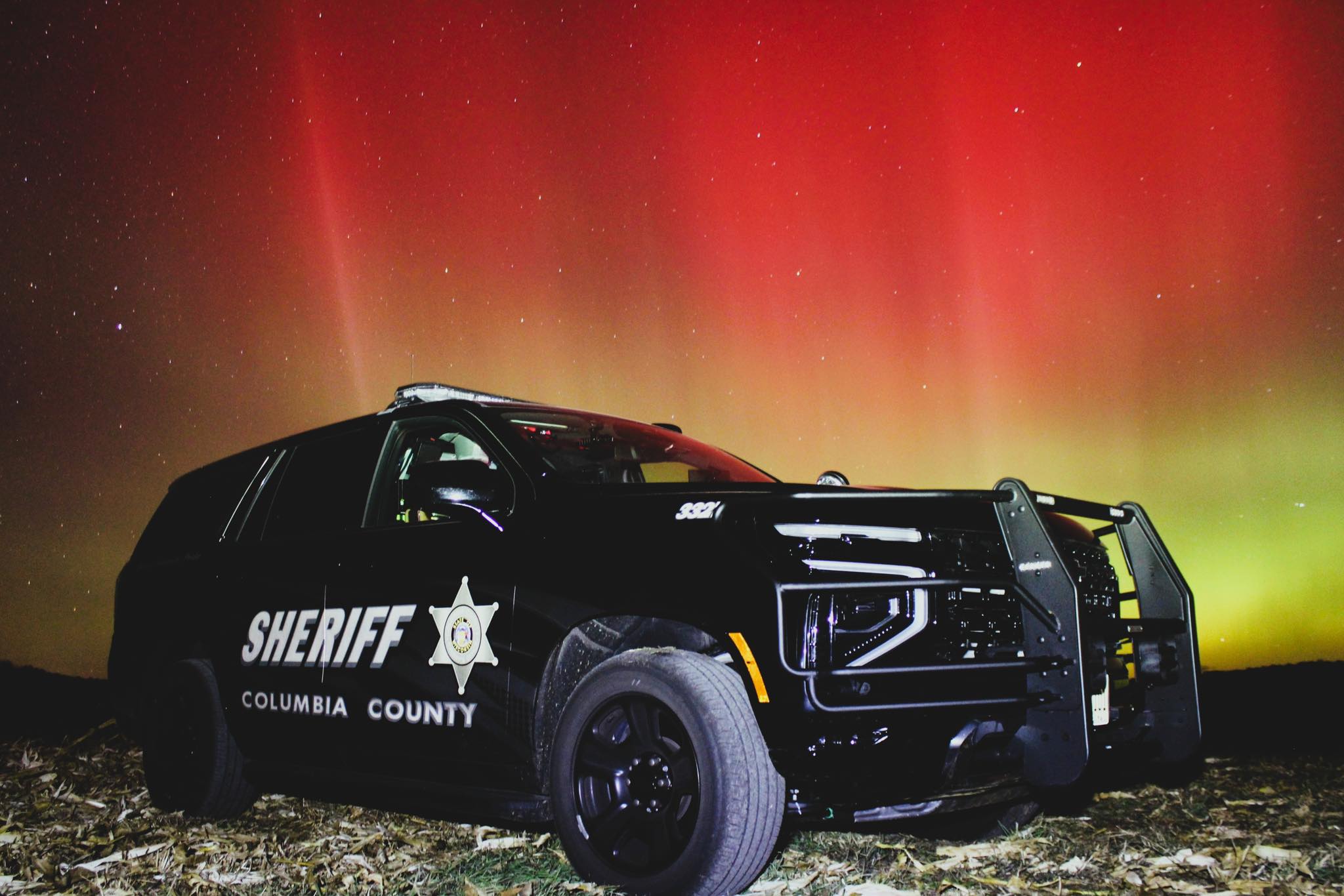 A police car parked in front of the northern lights